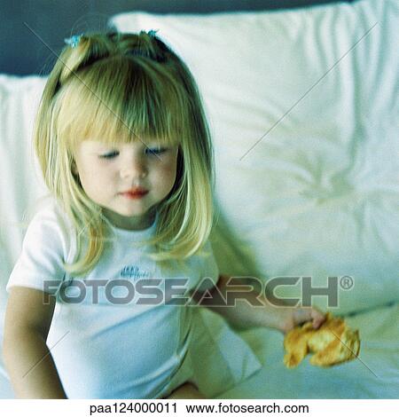 Girl sitting on bed, holding croissant View Large Photo Image Stock Image - Girl sitting on bed, holding croissant. Fotosearch