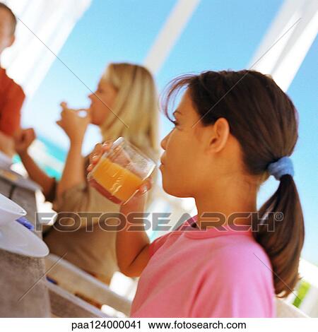 Girl sitting with family, drinking from glass, side view View Large Photo Image Stock Image - Girl sitting with family, drinking from glass, side view. Fotosearch