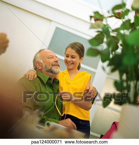 Stock Image - Mature man and girl with arms around each other, smiling. Fotosearch