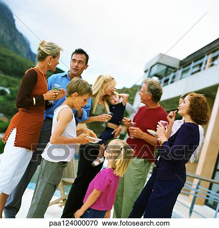 Stock Image - People standing and holding glasses, outside. Fotosearch