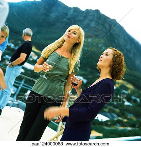 People standing and holding glasses, outside, mountain in background View Large Photo Image Stock Photo - People standing and holding glasses, outside, mountain in background. Fotosearch