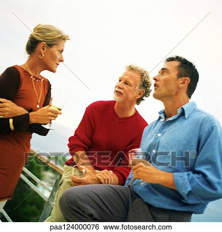 Two men and woman standing and holding glasses View Large Photo Image Stock Photograph - Two men and woman standing and holding glasses. Fotosearch