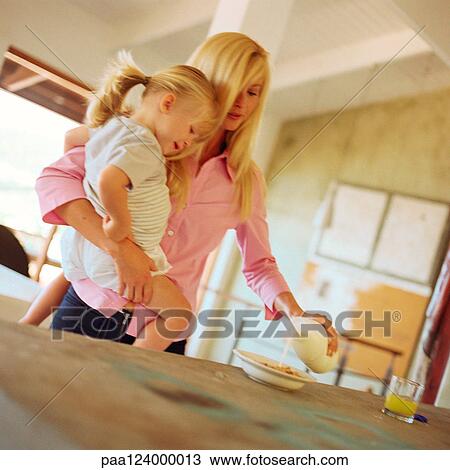 Woman carrying daughter, pouring milk into bowl View Large Photo Image Stock Image - Woman carrying daughter, pouring milk into bowl. Fotosearch