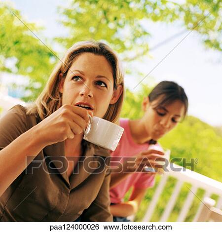 Stock Photograph - Woman holding teacup, girl holding glass. Fotosearch