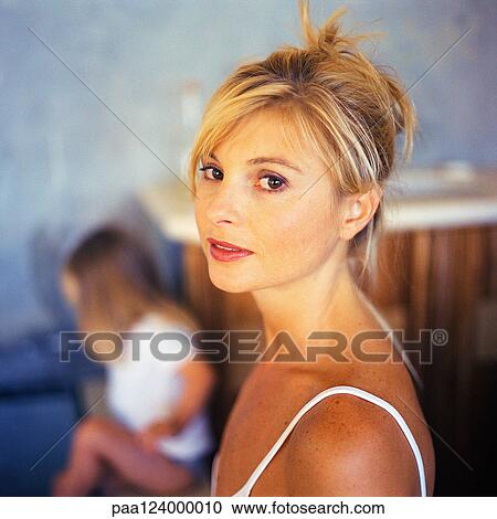 Woman looking into camera, child in background, portrait View Large Photo Image Stock Image - Woman looking into camera, child in background, portrait. Fotosearch