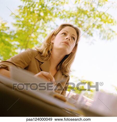 Woman sitting at table outside, low angle view View Large Photo Image Stock Photo - Woman sitting at table outside, low angle view. Fotosearch
