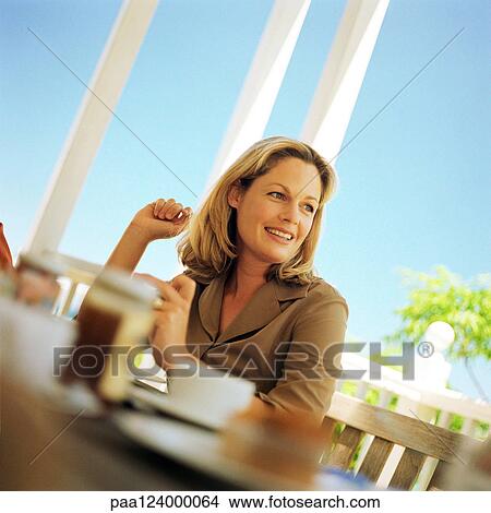 Woman sitting at table, smiling View Large Photo Image Picture - Woman sitting at table, smiling. Fotosearch