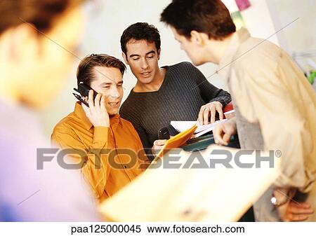 Businessmen in office, one using cell phone View Large Photo Image Stock Photography - Businessmen in office, one using cell phone. Fotosearch