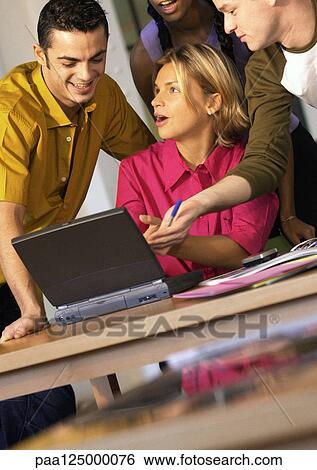 Four people grouped around laptop computer View Large Photo Image Stock Photograph - Four people grouped around laptop computer. Fotosearch