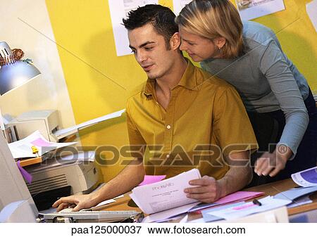 Stock Photo - Man and woman using computer, woman looking over man's shoulder. Fotosearch