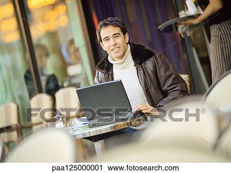 Man using laptop computer on cafe terrace View Large Photo Image Stock Image - Man using laptop computer on cafe terrace. Fotosearch