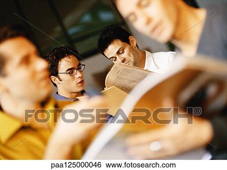 Men in office, looking at documents, blurred View Large Photo Image Stock Photograph - Men in office, looking at documents, blurred. Fotosearch