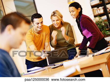 Stock Photograph - People in office, three people looking at laptop computer. Fotosearch