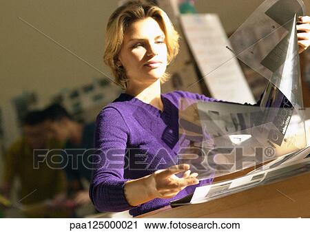 Stock Image - People in office, woman examining transparencies. Fotosearch
