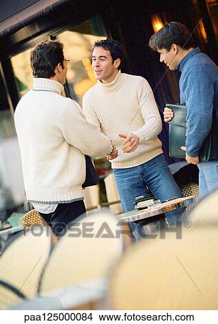 Picture - Three men at cafe terrace, two shaking hands. Fotosearch