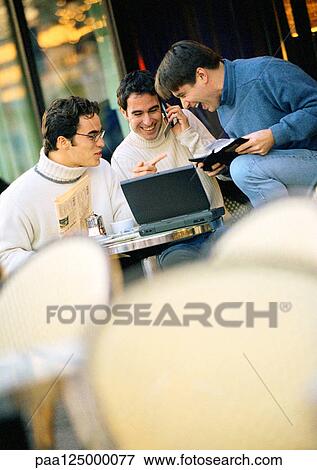 Stock Photo - Three men sitting at cafe terrace with laptop computer. Fotosearch