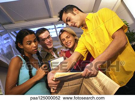 Two men and two women looking at newspaper View Large Photo Image Stock Image - Two men and two women looking at newspaper. Fotosearch