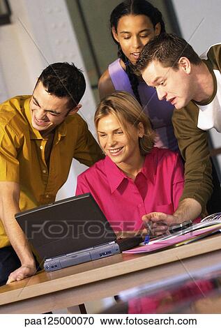Stock Image - Two men and two women using laptop computer. Fotosearch