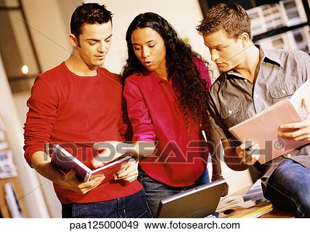 Two men and woman examining documents View Large Photo Image Stock Photo - Two men and woman examining documents. Fotosearch