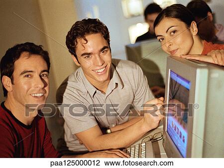 Two men and woman grouped around computer, smiling View Large Photo Image Stock Image - Two men and woman grouped around computer, smiling. Fotosearch