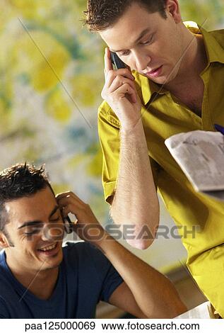 Stock Photo - Two men using cell phones, close-up. Fotosearch