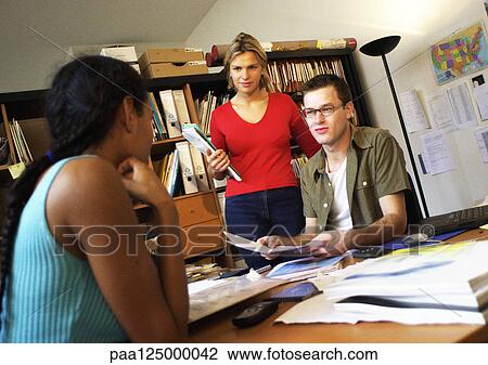 Two women and man at desk in office View Large Photo Image Stock Image - Two women and man at desk in office. Fotosearch