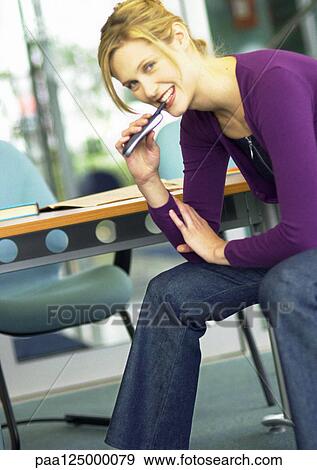 Woman holding cell phone next to mouth View Large Photo Image Stock Photo - Woman holding cell phone next to mouth. Fotosearch