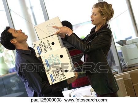 Woman piling boxes up in man's arms, side view View Large Photo Image Stock Photo - Woman piling boxes up in man's arms, side view. Fotosearch