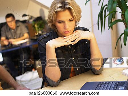 Stock Photograph - Woman with hands under chin in office. Fotosearch