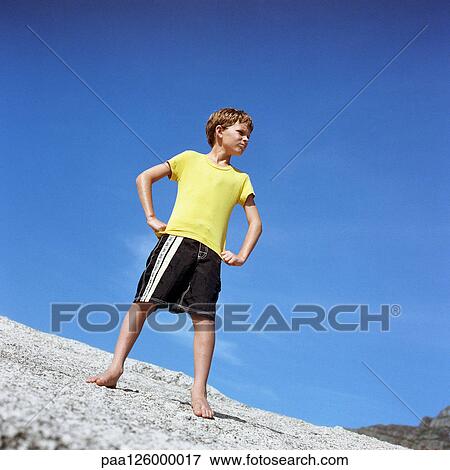 Boy standing with hands on hips, low angle view View Large Photo Image Stock Photo - Boy standing with hands on hips, low angle view. Fotosearch