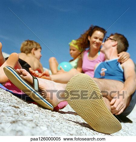 Stock Photography - Couple and children on beach, focus on man's feet in foreground. Fotosearch