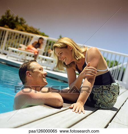 Couple at edge of swimming pool, smiling View Large Photo Image Stock Photography - Couple at edge of swimming pool, smiling. Fotosearch