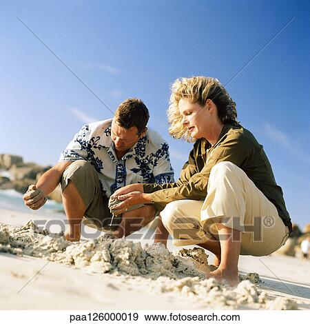 Couple digging in sand View Large Photo Image Stock Photo - Couple digging in sand. Fotosearch
