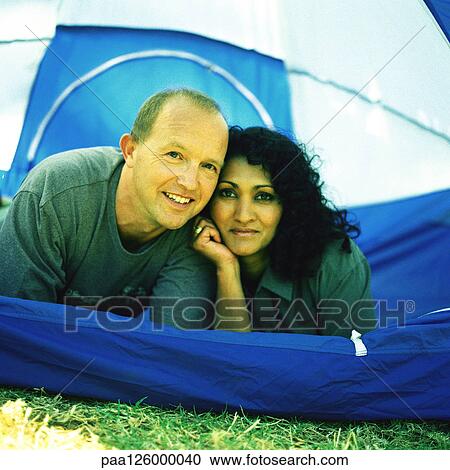 Stock Image - Couple lying tent, portrait. Fotosearch