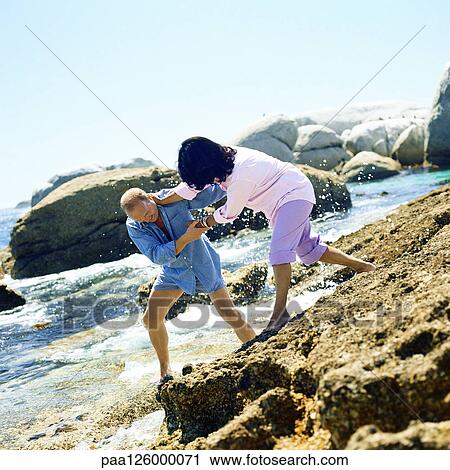 Stock Image - Couple playfighting on rocks. Fotosearch