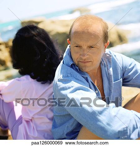 Couple sitting back to back outside View Large Photo Image Stock Photo - Couple sitting back to back outside. Fotosearch