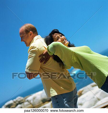 Couple standing back to back outside, smiling View Large Photo Image Stock Image - Couple standing back to back outside, smiling. Fotosearch