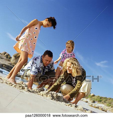 Family digging in sand View Large Photo Image Stock Photo - Family digging in sand. Fotosearch