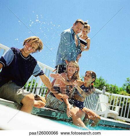 Stock Photograph - Family splashing water at edge of swimming pool. Fotosearch