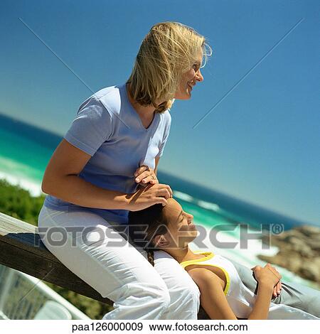 Girl with head on mother's lap, sea in background View Large Photo Image Stock Photo - Girl with head on mother's lap, sea in background. Fotosearch