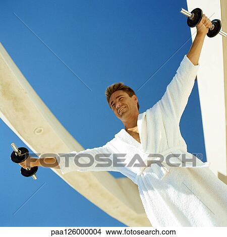 Man lifting weights in bathrobe, low angle view View Large Photo Image Picture - Man lifting weights in bathrobe, low angle view. Fotosearch