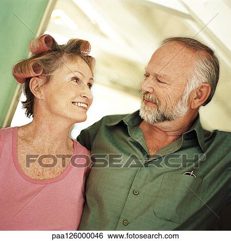 Stock Photograph - Mature couple looking at each other, woman with rollers in hair, portrait. Fotosearch
