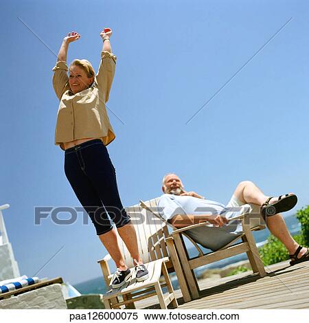 Mature couple outside, woman standing up on deckchair View Large Photo Image Stock Photography - Mature couple outside, woman standing up on deckchair. Fotosearch