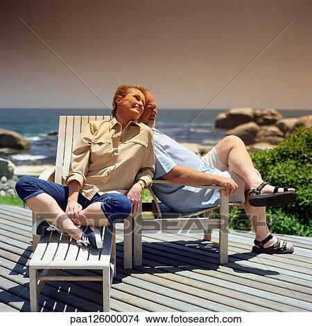 Mature couple sitting in deckchairs outside View Large Photo Image Picture - Mature couple sitting in deckchairs outside. Fotosearch
