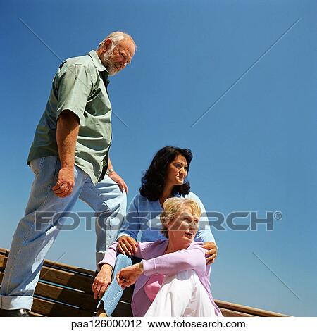 Stock Image - Mature man and two women outside. Fotosearch