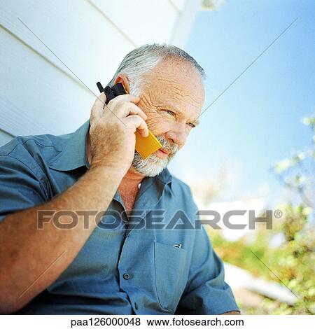 Stock Photo - Mature man using cell phone, outside. Fotosearch