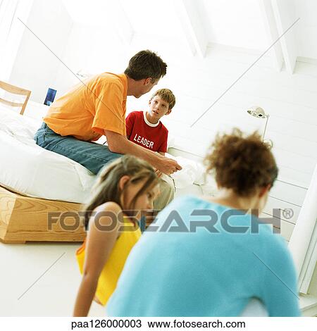 Stock Image - Parents and children sitting in bedroom. Fotosearch