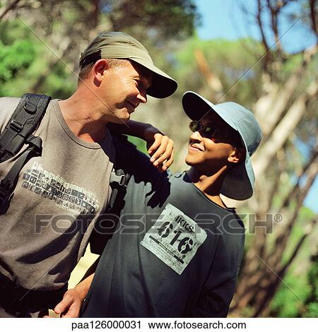 Stock Image - Teenage boy and man hiking, side by side. Fotosearch