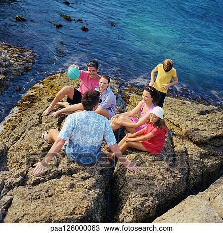 Stock Image - Two couples and children on rock, high angle view. Fotosearch