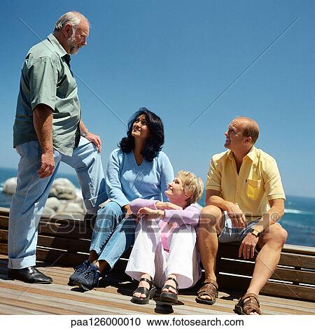 Stock Image - Two mature couples, sea in background. Fotosearch